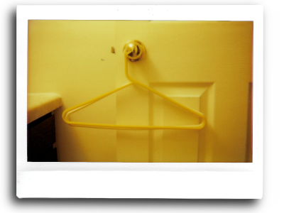 an instant picture of a yellow hanger hanging on the gold doorknob of a white door