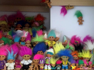 a shelf full of bright-haired troll toys