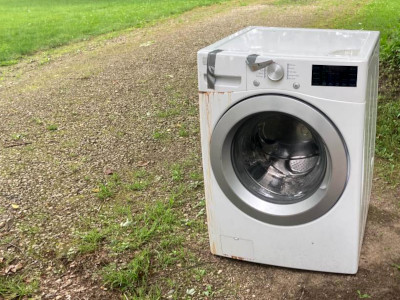 a white washing machine sitting out by a driveway